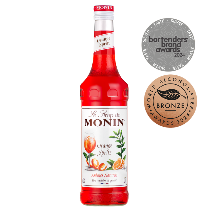 Image of a bottle of MONIN Orange Spritz syrup, a red-orange syrup with a label that features orange slices and green leaves. Perfect for cocktails and mocktails, the bottle is adorned with silver "Bartenders Brand Awards 2024" and bronze "World Alcohol-Free Awards 2024" medals.