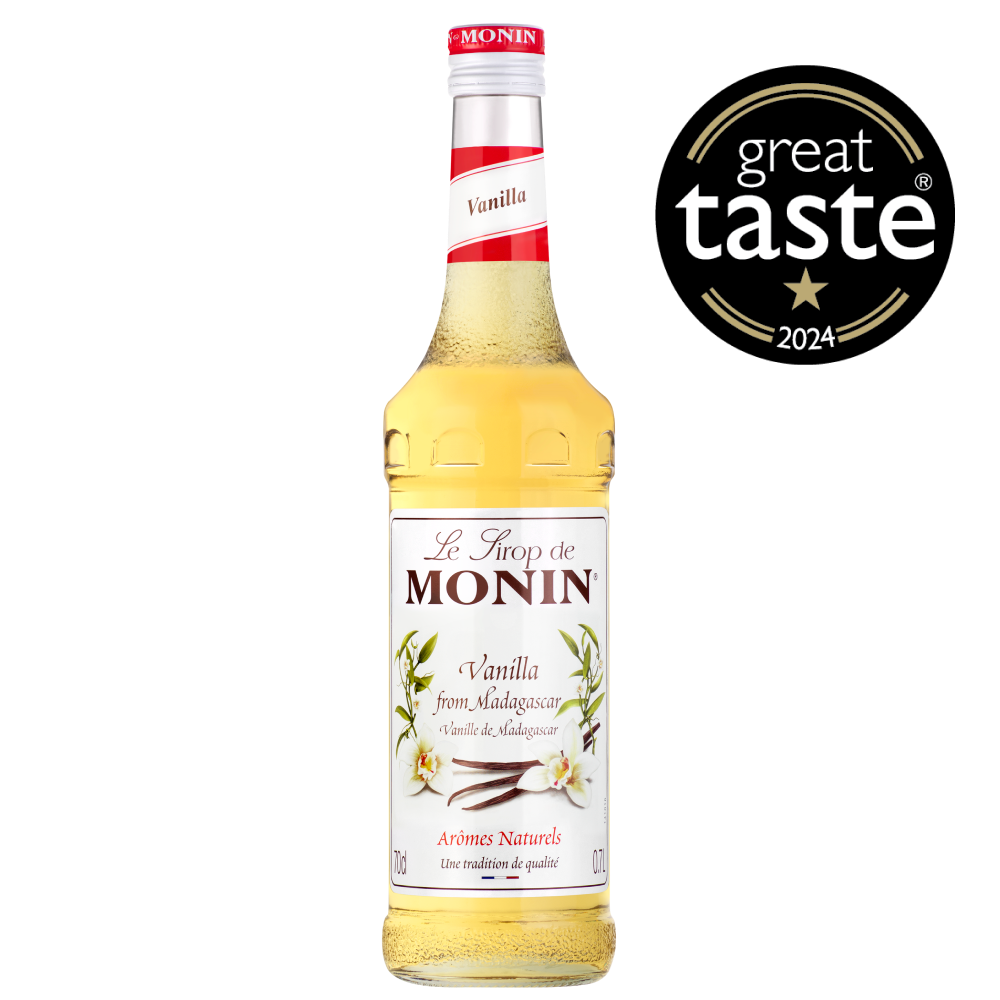 A 700ml bottle of MONIN Vanilla Syrup, labeled "Le Sirop de Monin," features vanilla flowers with the text "Vanilla from Madagascan Vanilla beans" and "Arômes Naturels." The bottle has a red cap and top, and the light golden syrup inside is ideal for various beverage applications.