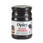 A jar of Opies Black Cherries With Kirsch, a luxurious treat featuring cherries preserved in Kirsch-infused syrup. The label displays enticing images of cherries and desserts, with text emphasizing its perfect use to adorn cakes or elevate indulgent desserts such as Black Forest gateau or glazed ham. The jar boasts a black lid and a transparent glass body, showcasing the rich contents within.