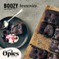 A wooden board holds several chocolate brownies with a dusting of powdered sugar. Nearby, a plate features a serving of the brownies crowned with cream and luxurious Opies Black Cherries With Kirsch. The word "BOOZY brownies" is written in black, and the "Opies since 1880" logo is displayed at the bottom left.