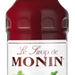 A 700ml bottle of MONIN Strawberry Syrup is perfect for enhancing beverages and mixed drinks. The label features images of strawberries and strawberry flowers, along with the text "Arômes Naturels" and "Une tradition de qualité." The bottle is topped with a red cap bearing the brand name "MONIN" in white.